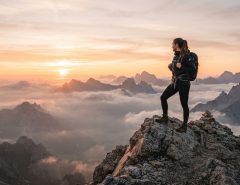 A person standing on a mountain peak watching the sunrise.