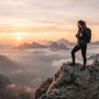 A person standing on a mountain peak watching the sunrise.