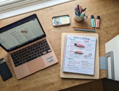 Student reviewing a digital academic portfolio layout on a laptop at a organized desk setup.