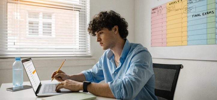 Young male student planning academic roadmap on laptop desk.