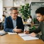 Male career counselor advising a professional man in a bright modern office.